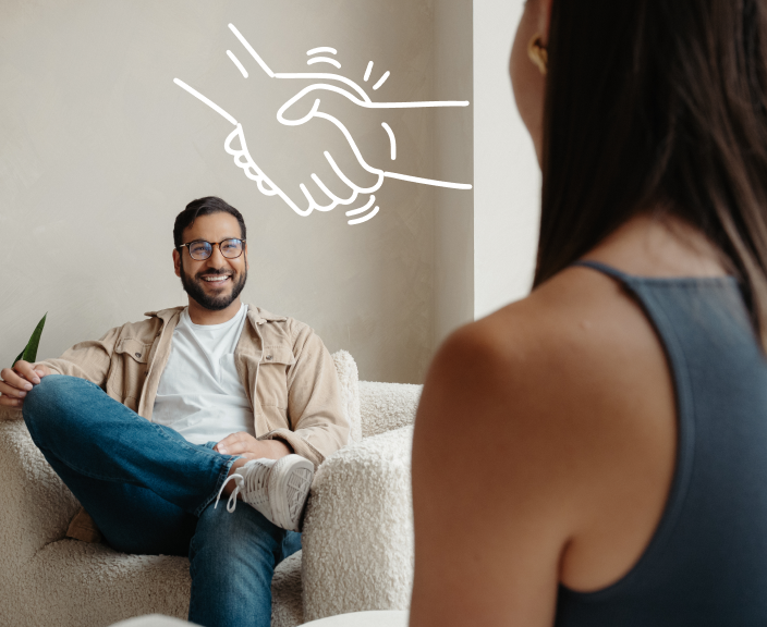 Man sitting on couch smiling at woman with handshake illustration above representing agreement or partnership